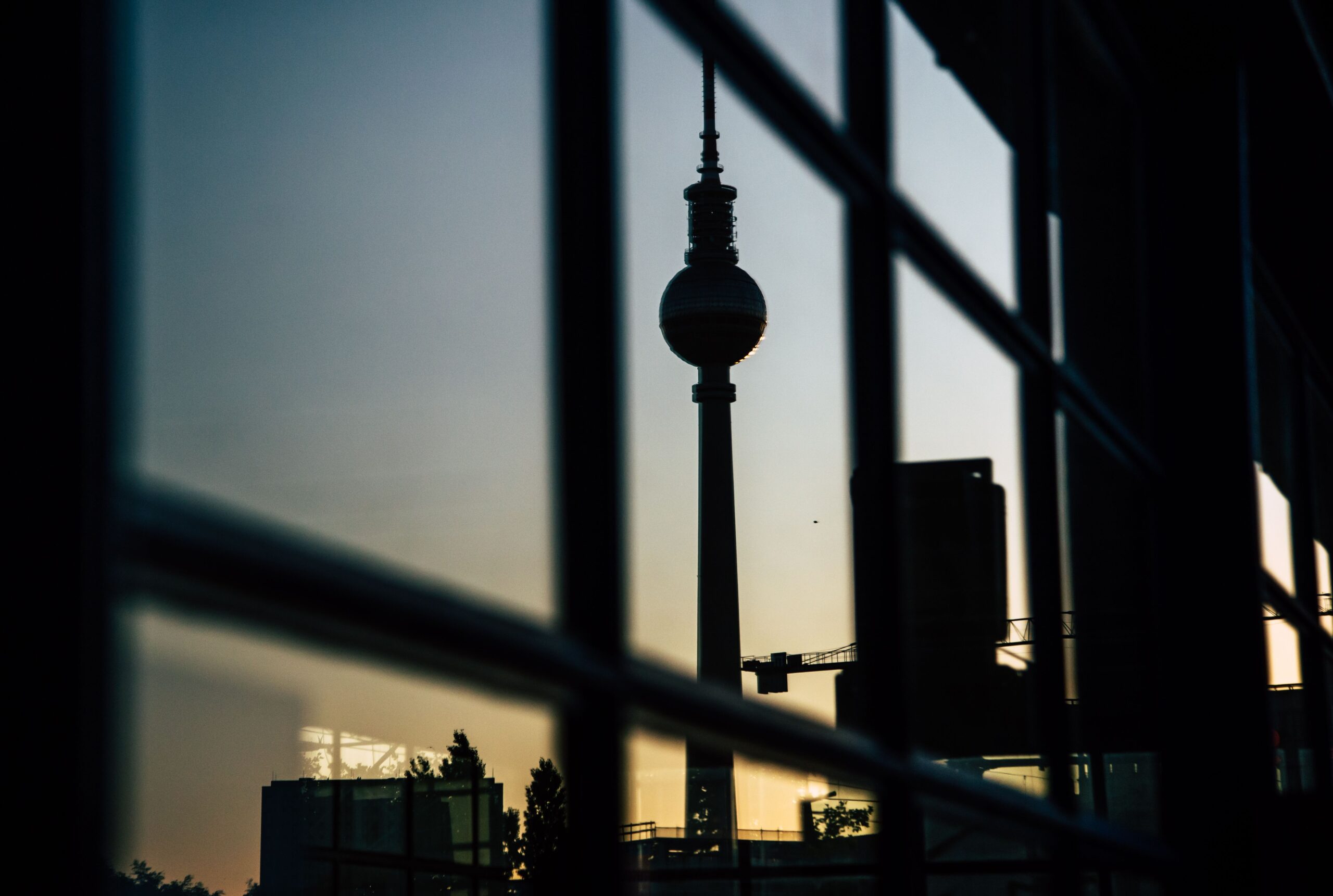 Artistic reflection of Berlin's TV Tower in a window during sunset, creating a dramatic skyline silhouette.